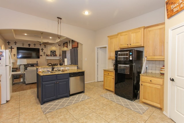 kitchen featuring black fridge, sink, stainless steel dishwasher, white fridge, and light stone counters