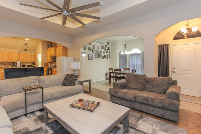 tiled living room with ceiling fan with notable chandelier and lofted ceiling