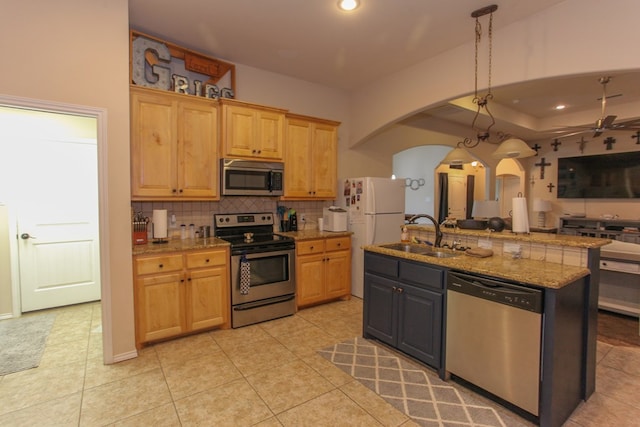 kitchen featuring appliances with stainless steel finishes, ceiling fan, sink, light tile patterned floors, and a center island with sink