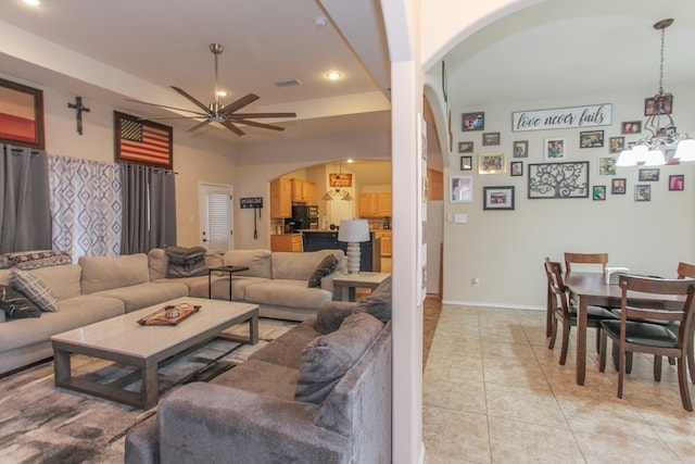 living room with light tile patterned floors and ceiling fan with notable chandelier