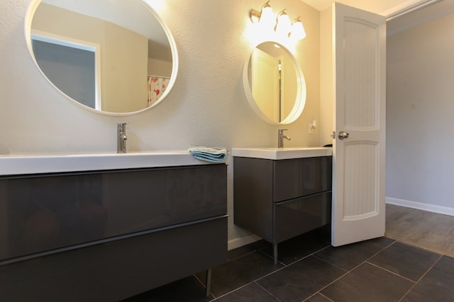 bathroom featuring a sink, tile patterned floors, baseboards, and two vanities
