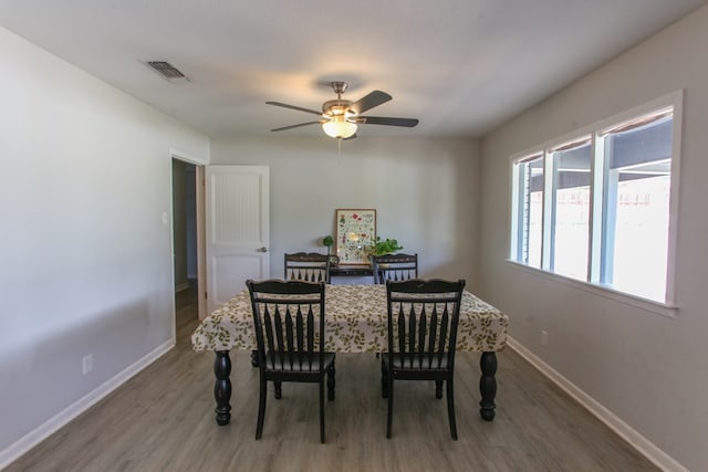 dining area with baseboards, a ceiling fan, wood finished floors, and visible vents