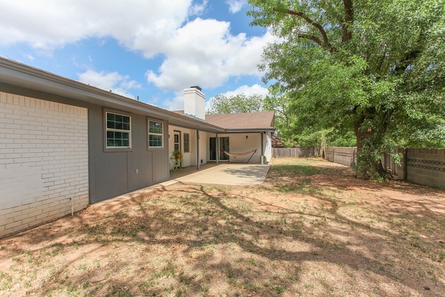 back of property featuring a fenced backyard, a chimney, a patio area, and brick siding