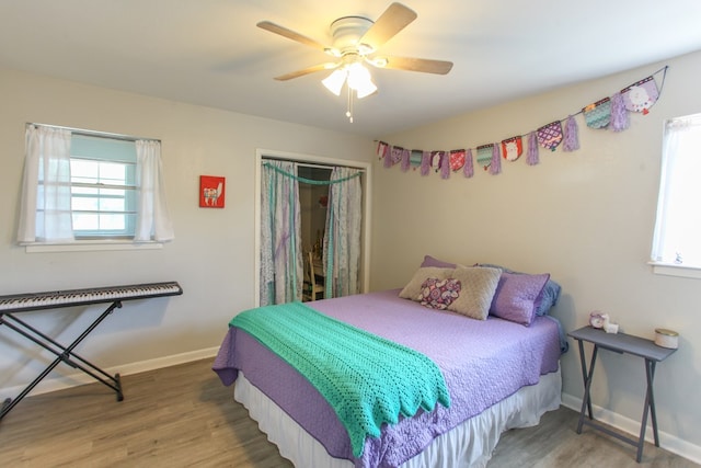 bedroom featuring baseboards, a closet, wood finished floors, and multiple windows