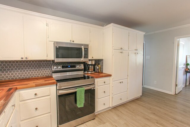 kitchen featuring appliances with stainless steel finishes, tasteful backsplash, wood counters, light wood-type flooring, and ornamental molding