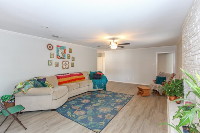living area with ceiling fan, visible vents, wood finished floors, baseboards, and ornamental molding