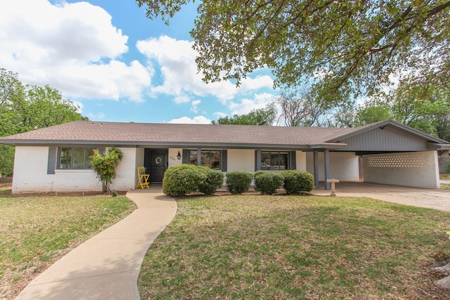 single story home featuring a shingled roof, brick siding, an attached carport, a front yard, and driveway