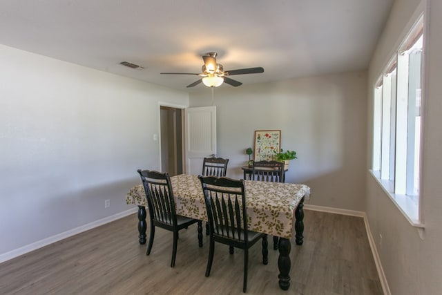 dining room featuring visible vents, a ceiling fan, baseboards, and wood finished floors