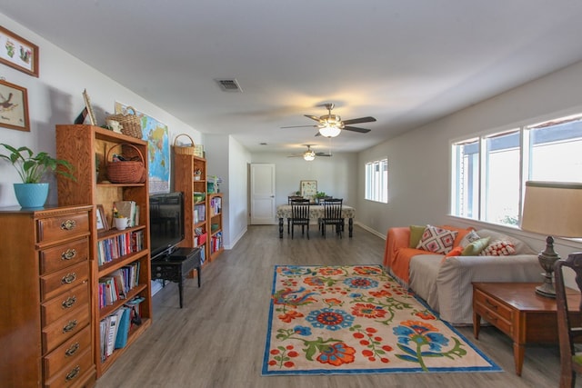 living room featuring baseboards, ceiling fan, wood finished floors, and visible vents