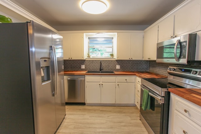 kitchen with backsplash, appliances with stainless steel finishes, butcher block counters, and a sink