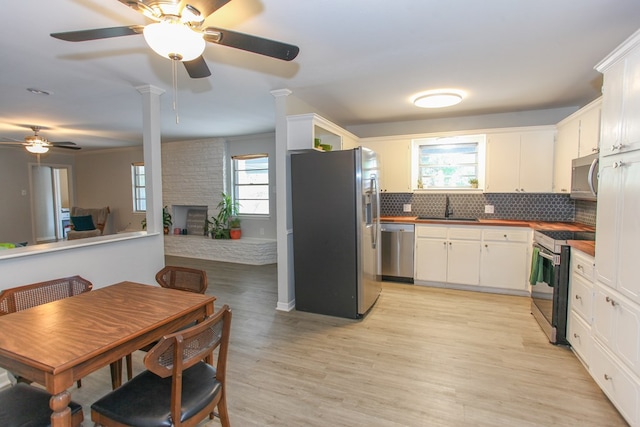 kitchen featuring a sink, stainless steel appliances, a ceiling fan, white cabinetry, and tasteful backsplash