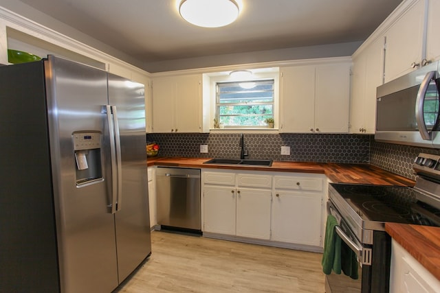 kitchen with a sink, butcher block counters, tasteful backsplash, and stainless steel appliances