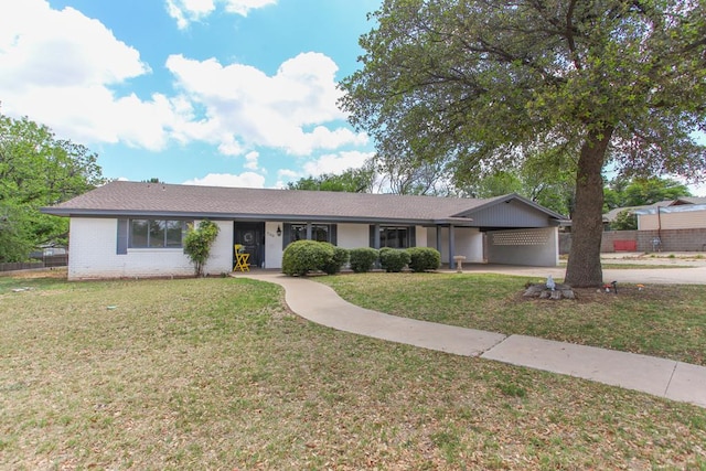 ranch-style home with driveway, a carport, brick siding, fence, and a front lawn