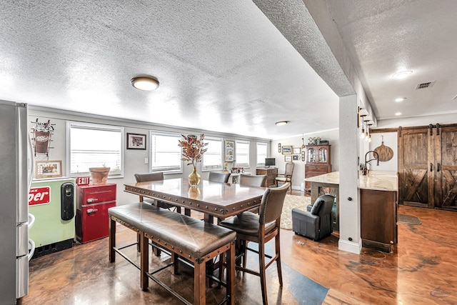 dining space featuring a barn door and a textured ceiling