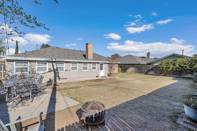 back of house with an outdoor fire pit, a yard, and a patio