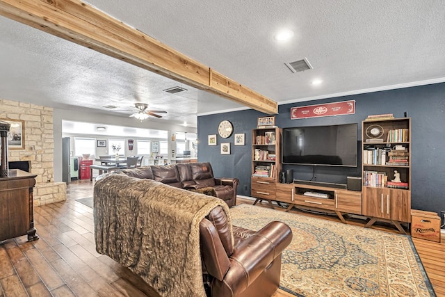 living room featuring ceiling fan, wood-type flooring, ornamental molding, and a textured ceiling