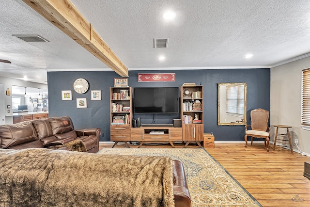 living room with wood-type flooring, a textured ceiling, crown molding, and beam ceiling