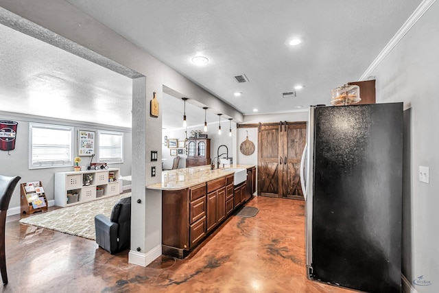 kitchen featuring a textured ceiling, concrete flooring, a barn door, and stainless steel fridge