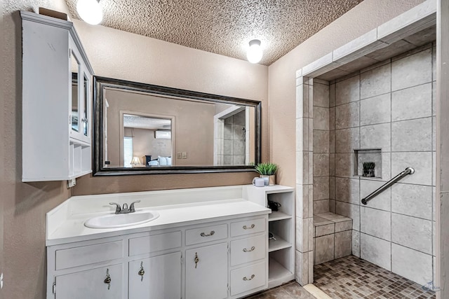 2821 Metz Dr, Midland, TX 79705 - full bath with a textured wall, vanity, a tile shower, and a textured ceiling