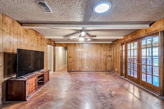 2821 Metz Dr, Midland, TX 79705 - unfurnished living room with wood walls, a textured ceiling, beamed ceiling, concrete floors, and french doors