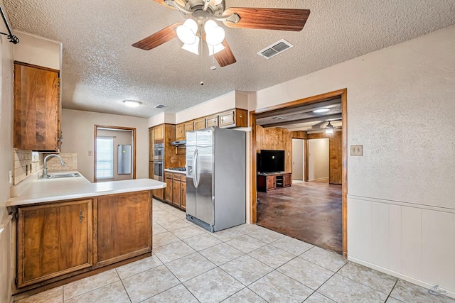 2821 Metz Dr, Midland, TX 79705 - kitchen featuring stainless steel fridge with ice dispenser, a sink, a textured ceiling, brown cabinets, and ceiling fan