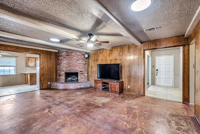 2821 Metz Dr, Midland, TX 79705 - unfurnished living room featuring wooden walls, ceiling fan, a textured ceiling, a brick fireplace, and beam ceiling