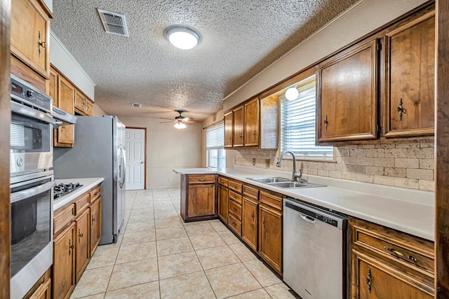 2821 Metz Dr, Midland, TX 79705 - kitchen featuring appliances with stainless steel finishes, a textured ceiling, a sink, ceiling fan, and a peninsula