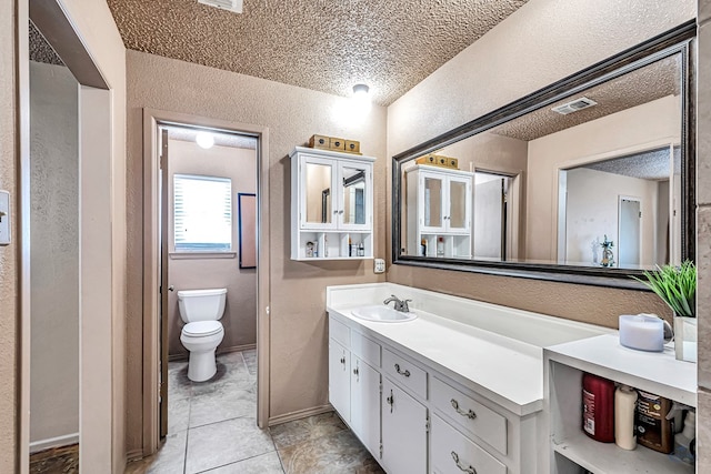 2821 Metz Dr, Midland, TX 79705 - bathroom with a textured wall, a textured ceiling, vanity, toilet, and tile patterned floors