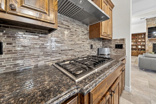 5514 Casa Grande Trl, Midland, TX 79707 - kitchen with wall chimney range hood, stainless steel gas stovetop, open floor plan, backsplash, and dark stone counters