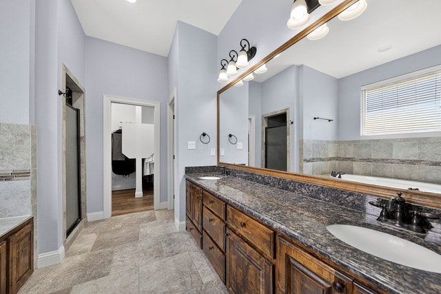 5514 Casa Grande Trl, Midland, TX 79707 - bathroom featuring double vanity, a garden tub, a shower stall, baseboards, and stone finish floors