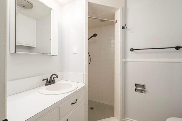 full bath with a tile shower and vanity