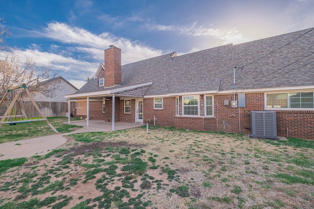 back of property featuring a playground, a chimney, a patio area, fence, and cooling unit