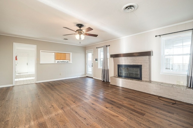 unfurnished living room with visible vents, ceiling fan, wood finished floors, crown molding, and a brick fireplace