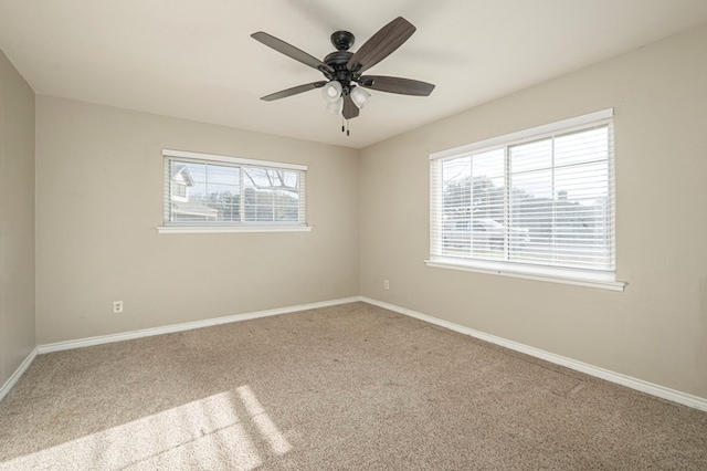 carpeted spare room featuring baseboards and a ceiling fan