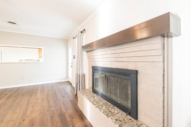 unfurnished living room featuring baseboards, visible vents, ornamental molding, wood finished floors, and a brick fireplace