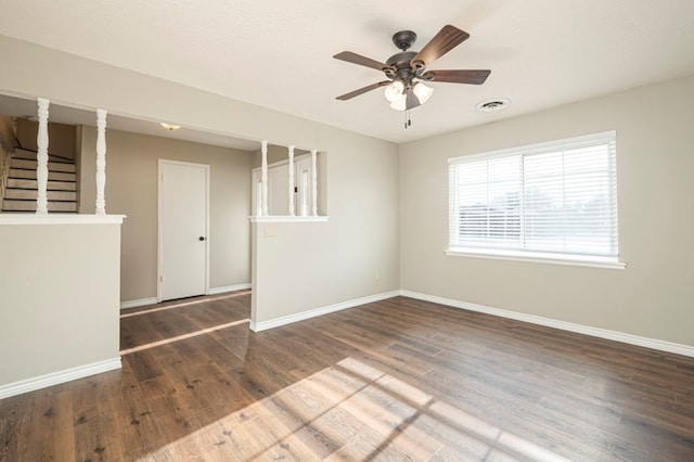 unfurnished room featuring wood finished floors, visible vents, a ceiling fan, stairs, and baseboards