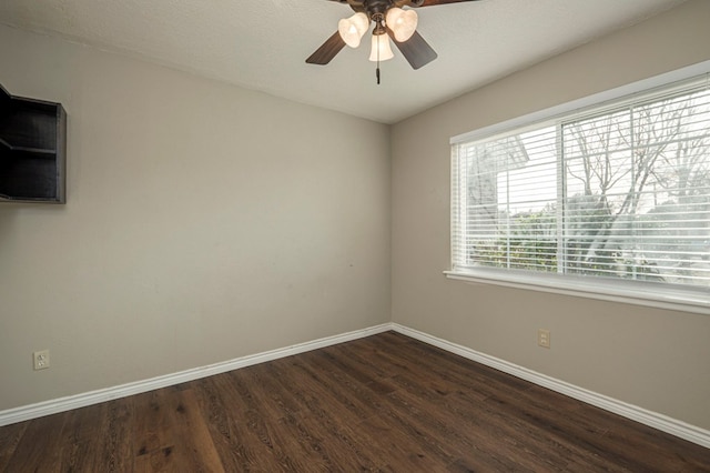 empty room with ceiling fan, dark wood-type flooring, and baseboards