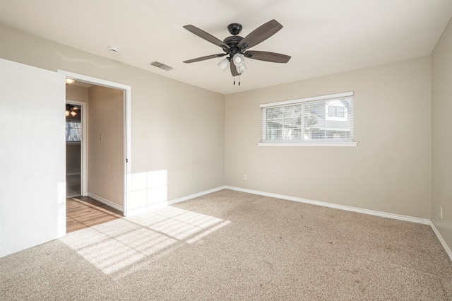 unfurnished room with light carpet, baseboards, visible vents, and ceiling fan