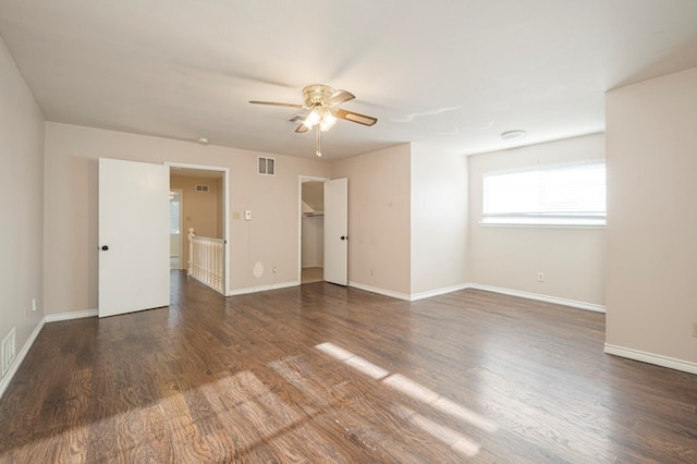 empty room featuring a ceiling fan, visible vents, baseboards, and wood finished floors