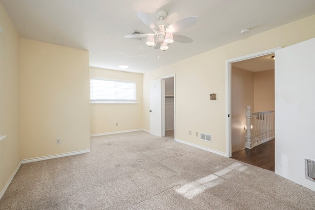 unfurnished bedroom featuring carpet, a walk in closet, visible vents, and baseboards