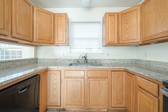 kitchen with light brown cabinets, stove, a sink, black dishwasher, and light stone countertops