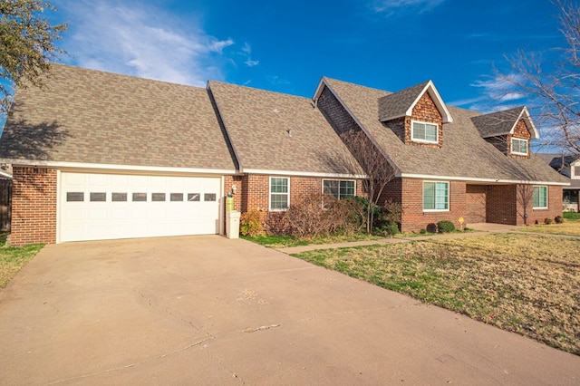 new england style home with an attached garage, a front yard, concrete driveway, and brick siding