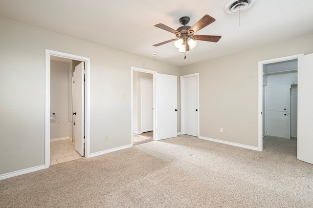 unfurnished bedroom with visible vents, baseboards, ensuite bath, a walk in closet, and carpet floors