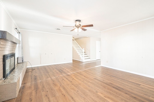 unfurnished living room featuring crown molding, light wood-type flooring, a fireplace, and stairway