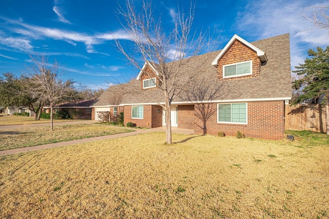 new england style home with a front lawn, an attached garage, fence, and brick siding