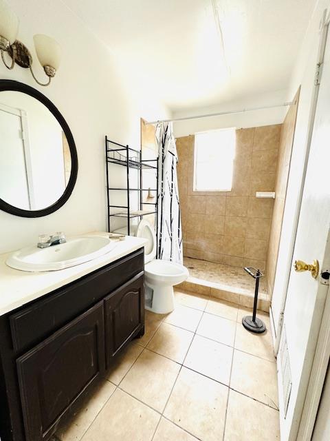 bathroom featuring toilet, vanity, tile patterned floors, and curtained shower