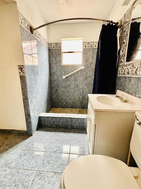 bathroom featuring tile patterned floors, vanity, toilet, and walk in shower