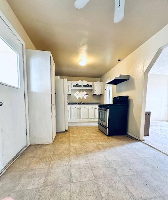 kitchen featuring white fridge, white cabinetry, ceiling fan, and stainless steel range oven