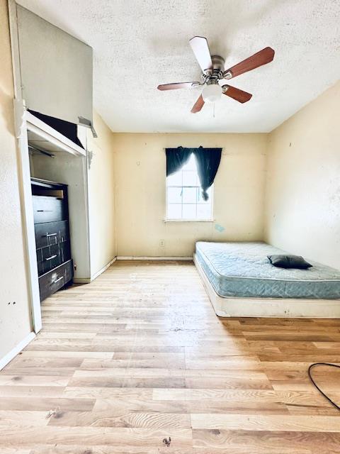 unfurnished bedroom with a textured ceiling, light hardwood / wood-style floors, and ceiling fan