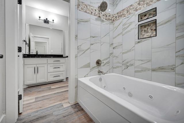 bathroom with hardwood / wood-style flooring, vanity, and tiled shower / bath